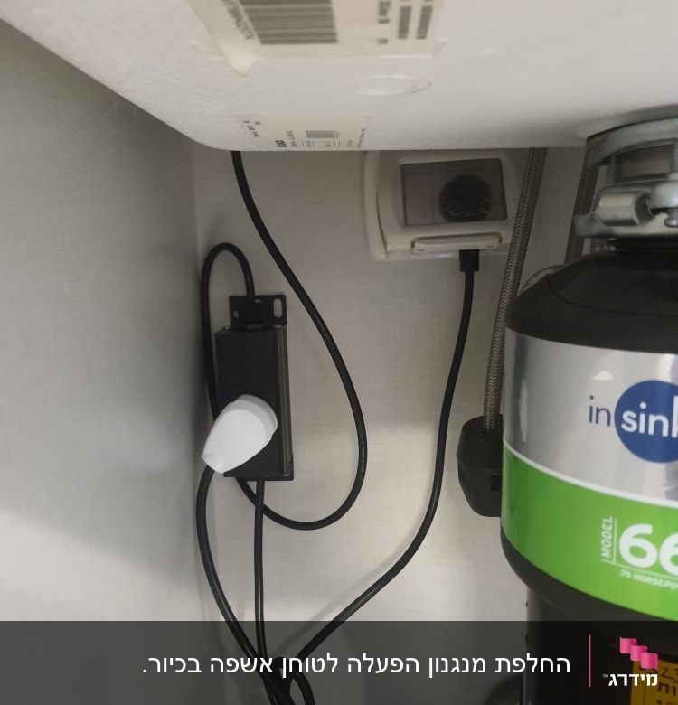 מתחת לכיור עם חוטי חשמל ומכשיר טוחן אשפה